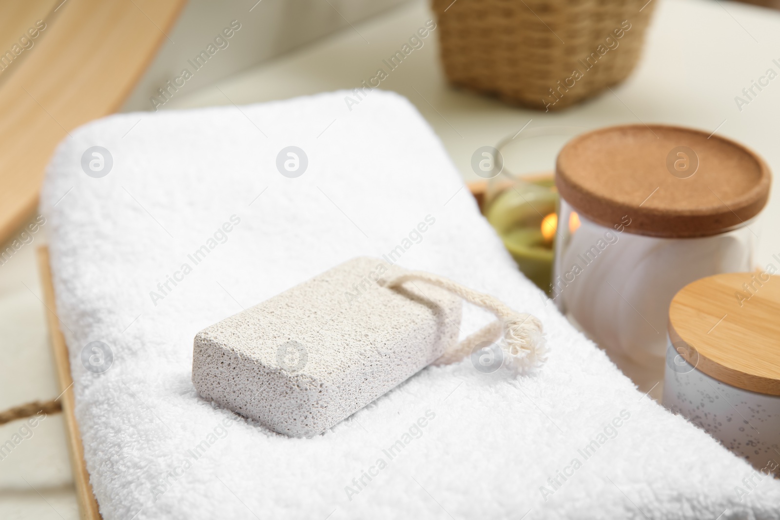 Photo of Pumice stone, towel and jars on white table, closeup