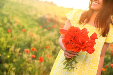 Photo of Woman with bouquet of poppies in field on sunny day, closeup. Space for text