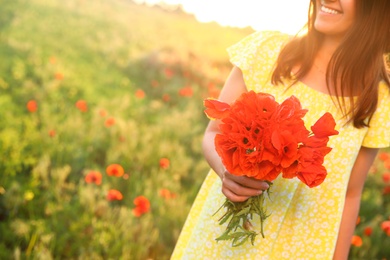 Woman with bouquet of poppies in field on sunny day, closeup. Space for text