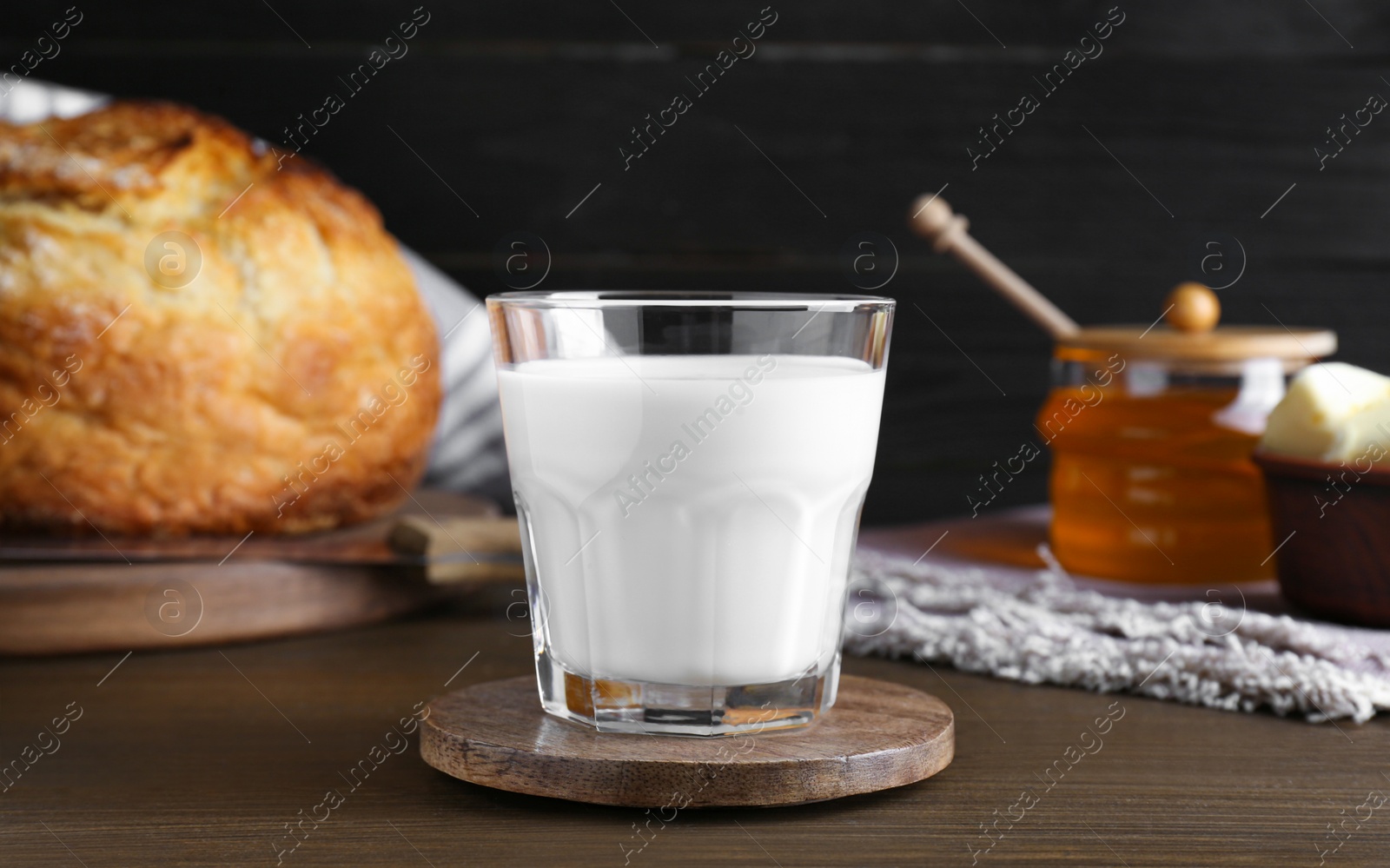 Photo of Glass with fresh milk, honey and bread on wooden table