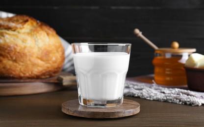 Photo of Glass with fresh milk, honey and bread on wooden table