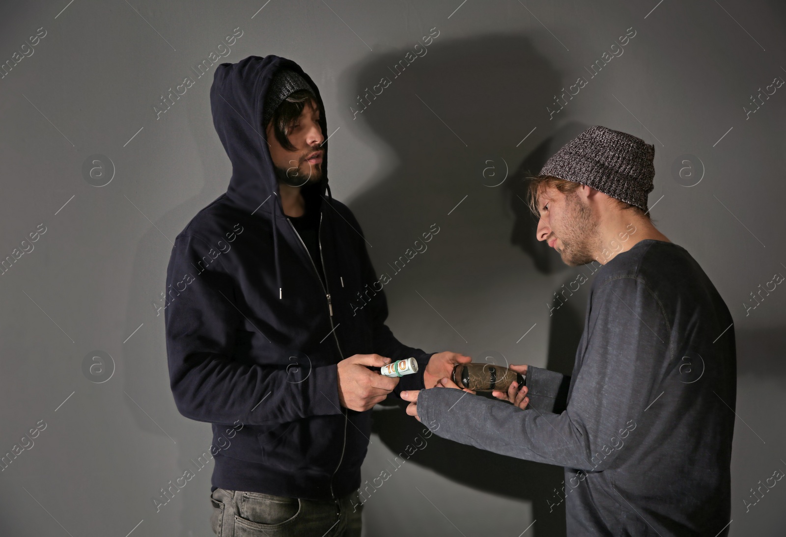 Photo of Addicted man buying drugs from dealer on grey background