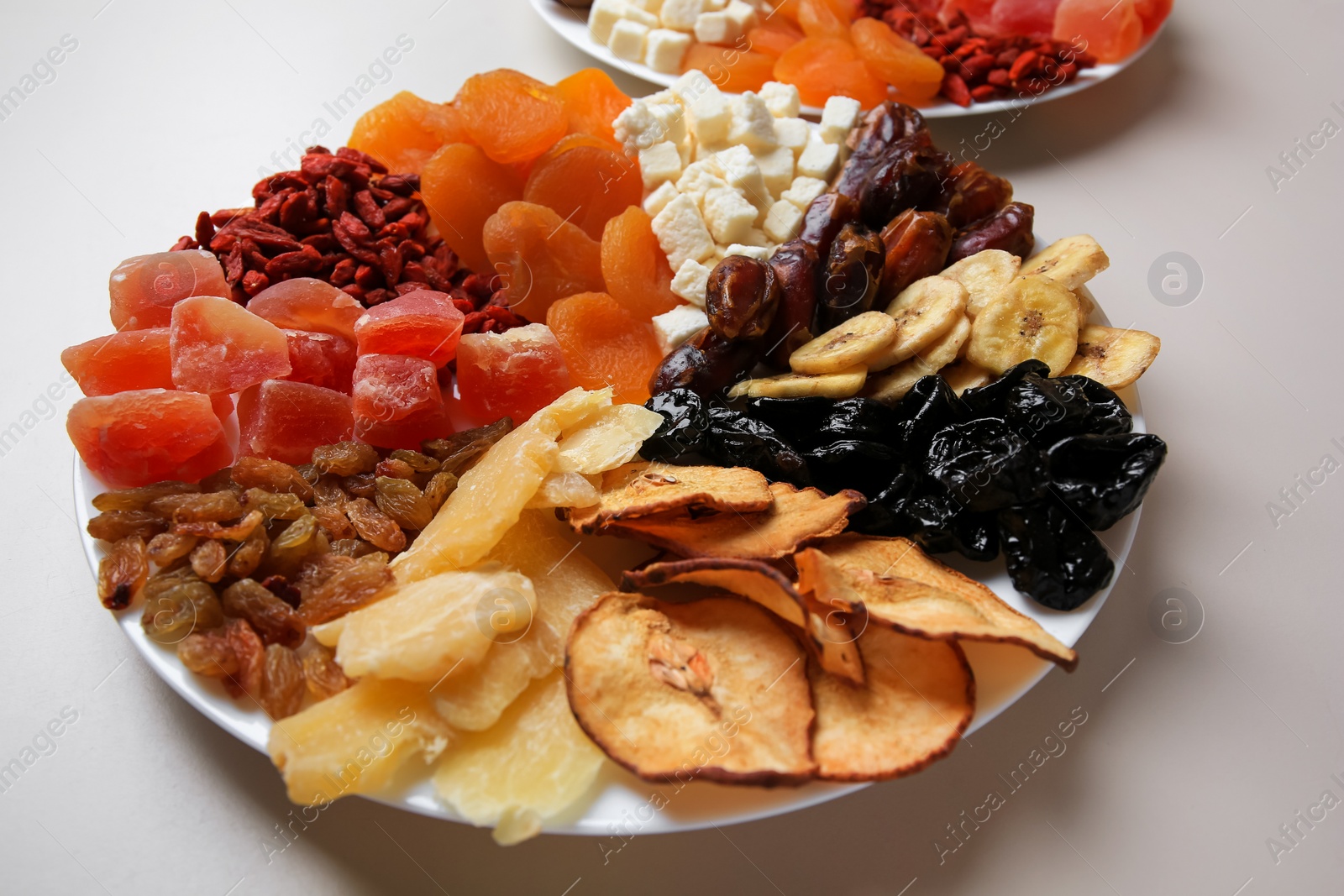 Photo of Plates with different dried fruits on white background