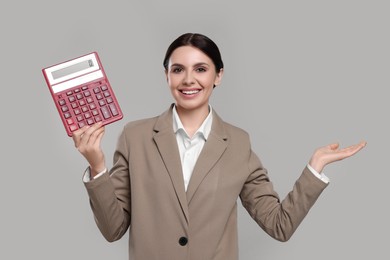 Happy accountant with calculator on grey background