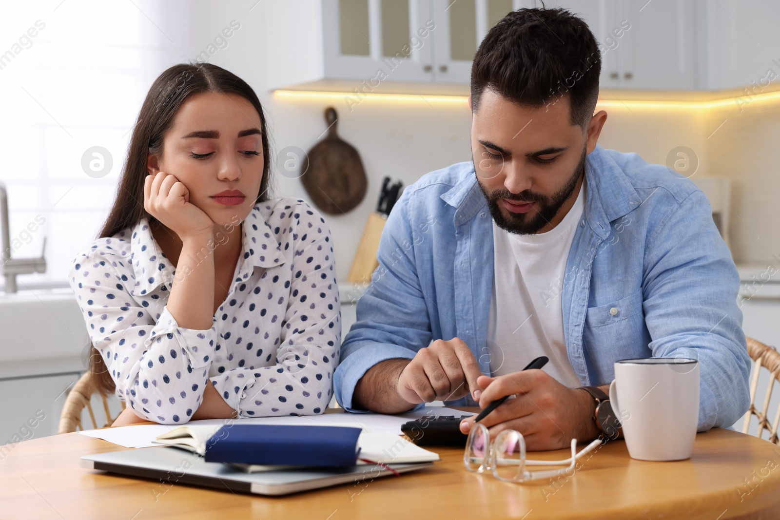 Photo of Young couple discussing family budget in kitchen