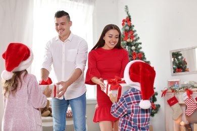 Happy parents and children exchanging gifts on Christmas morning at home