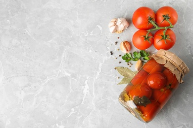 Photo of Flat lay composition with pickled tomatoes in glass jar on grey table, space for text