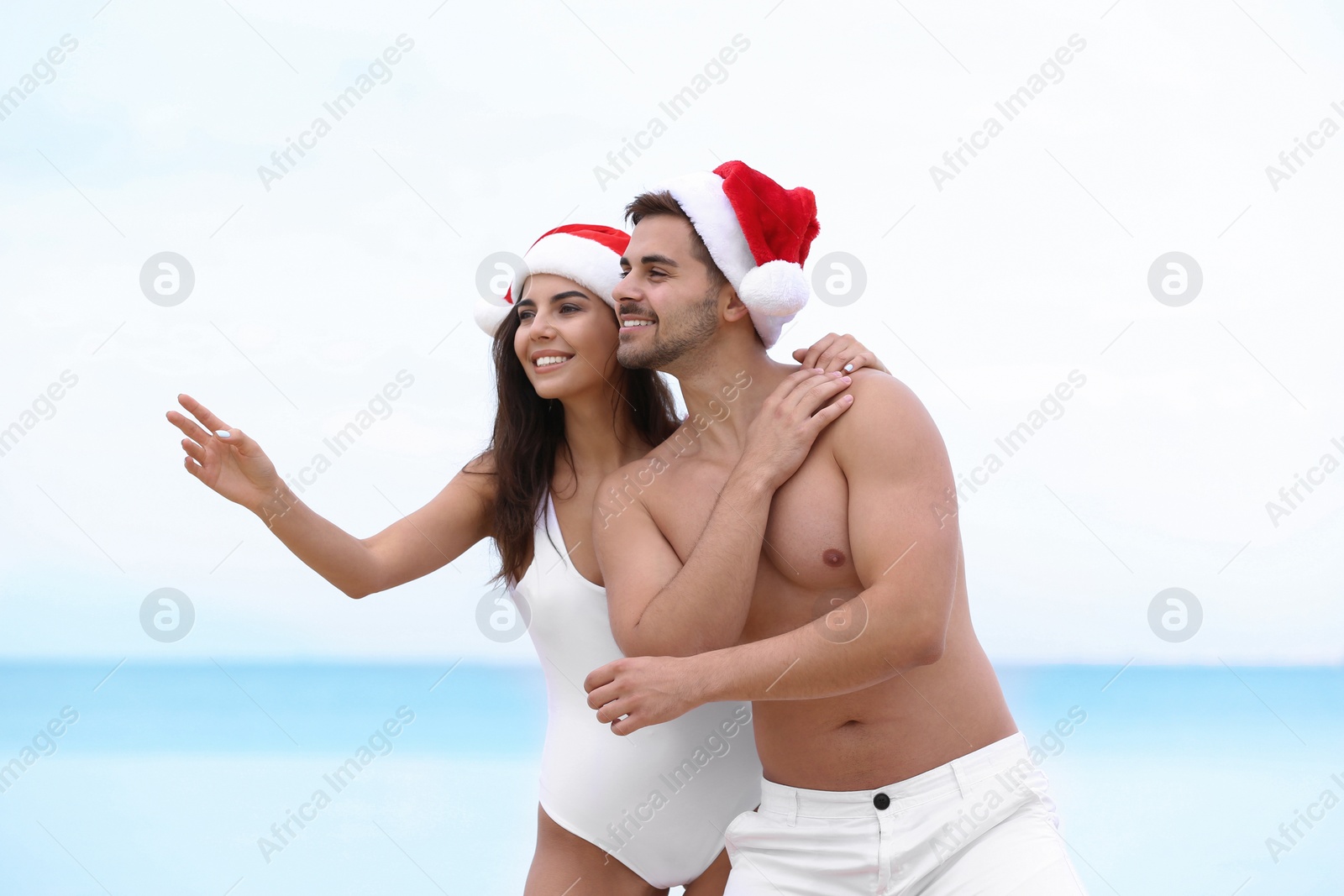 Photo of Happy young couple with Santa hats together on beach