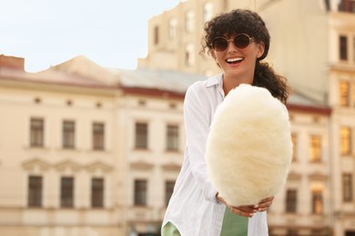Photo of Smiling woman with cotton candy on city street. Space for text