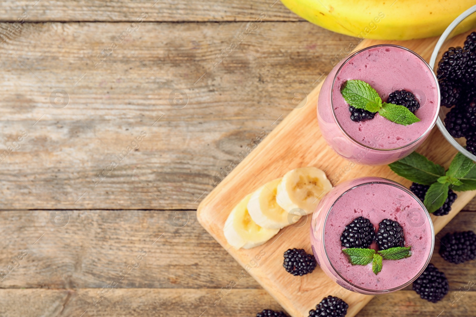 Photo of Flat lay composition with glasses of delicious blackberry smoothie on wooden background. Space for text