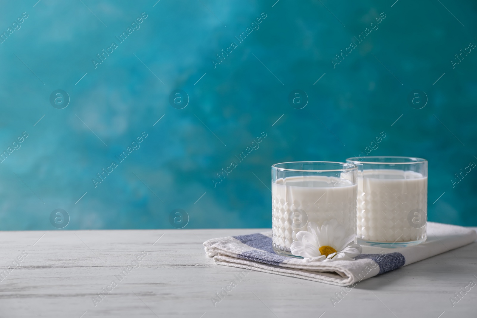 Photo of Two glasses of fresh milk on table against color background