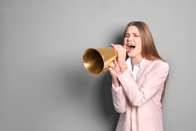 Photo of Young woman shouting into megaphone on grey background