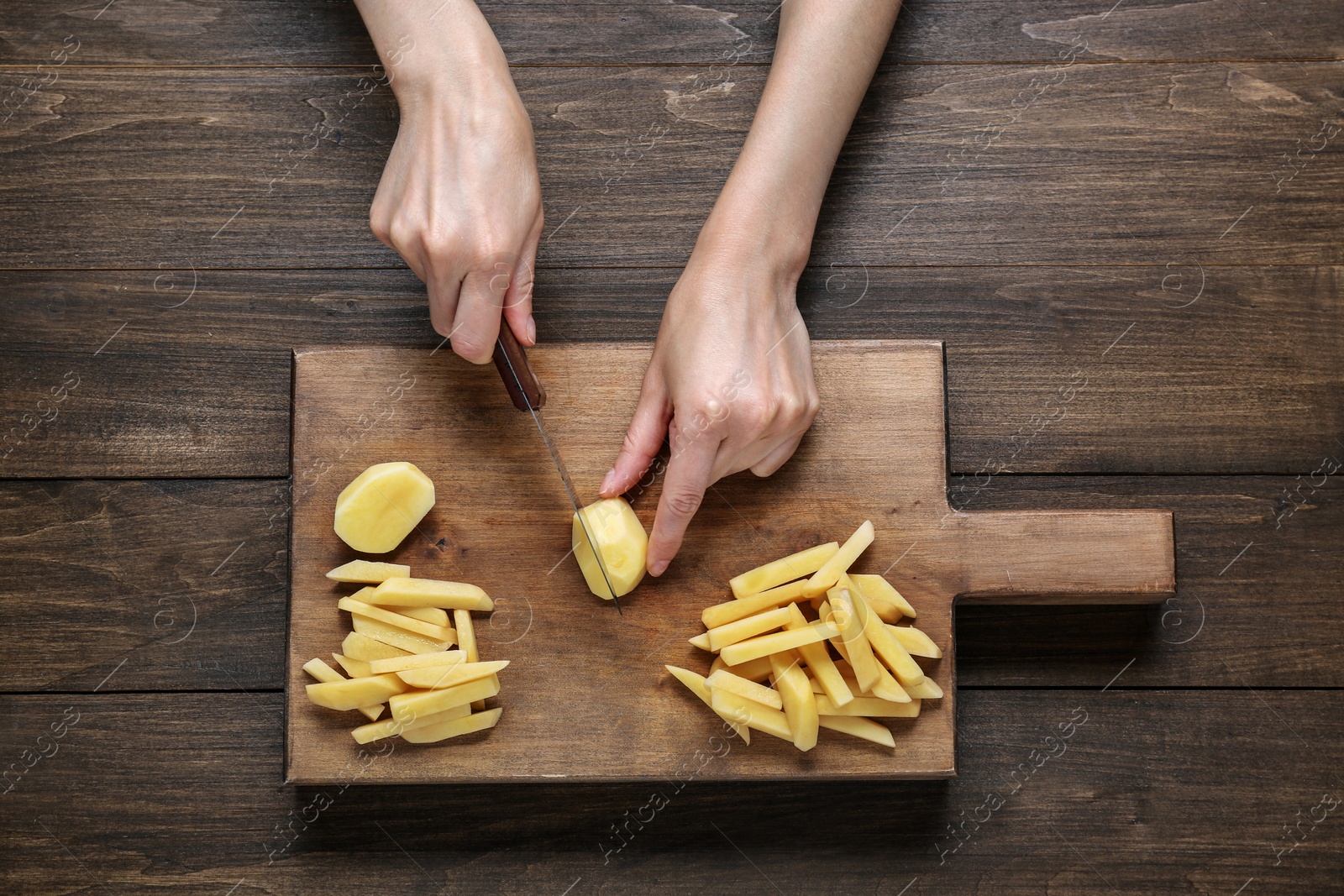 Photo of Woman cut potatoes at wooden table, top view