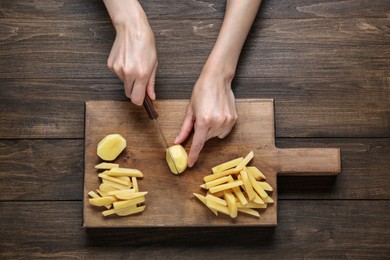 Photo of Woman cut potatoes at wooden table, top view