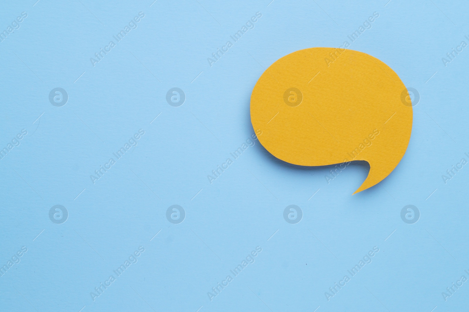 Photo of Paper speech bubble on light blue background, top view. Space for text