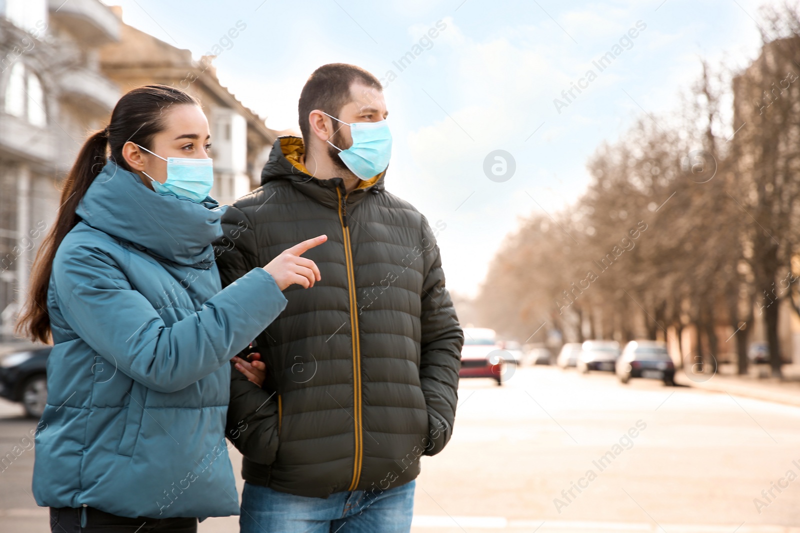 Photo of Couple wearing disposable masks outdoors. Dangerous virus