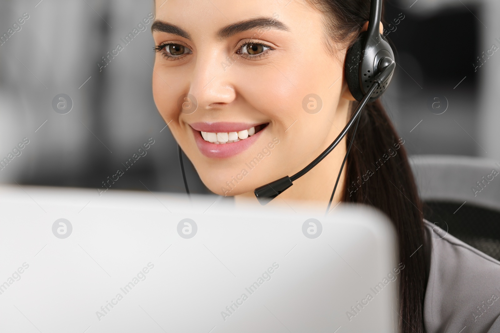 Photo of Hotline operator with headset working on computer in office