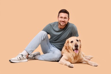 Photo of Man with adorable Labrador Retriever dog on beige background. Lovely pet