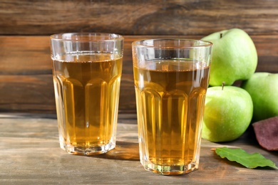 Two glasses of fresh apple juice on wooden table