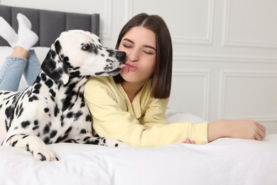 Beautiful woman with her adorable Dalmatian dog on bed at home. Lovely pet