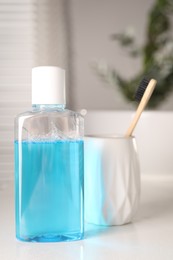 Bottle of mouthwash and toothbrush on white table in bathroom