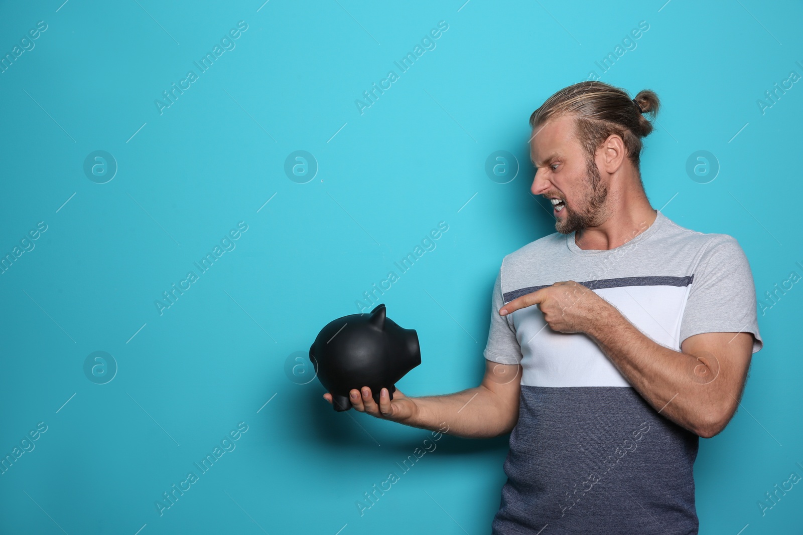 Photo of Emotional man with piggy bank on color background. Space for text