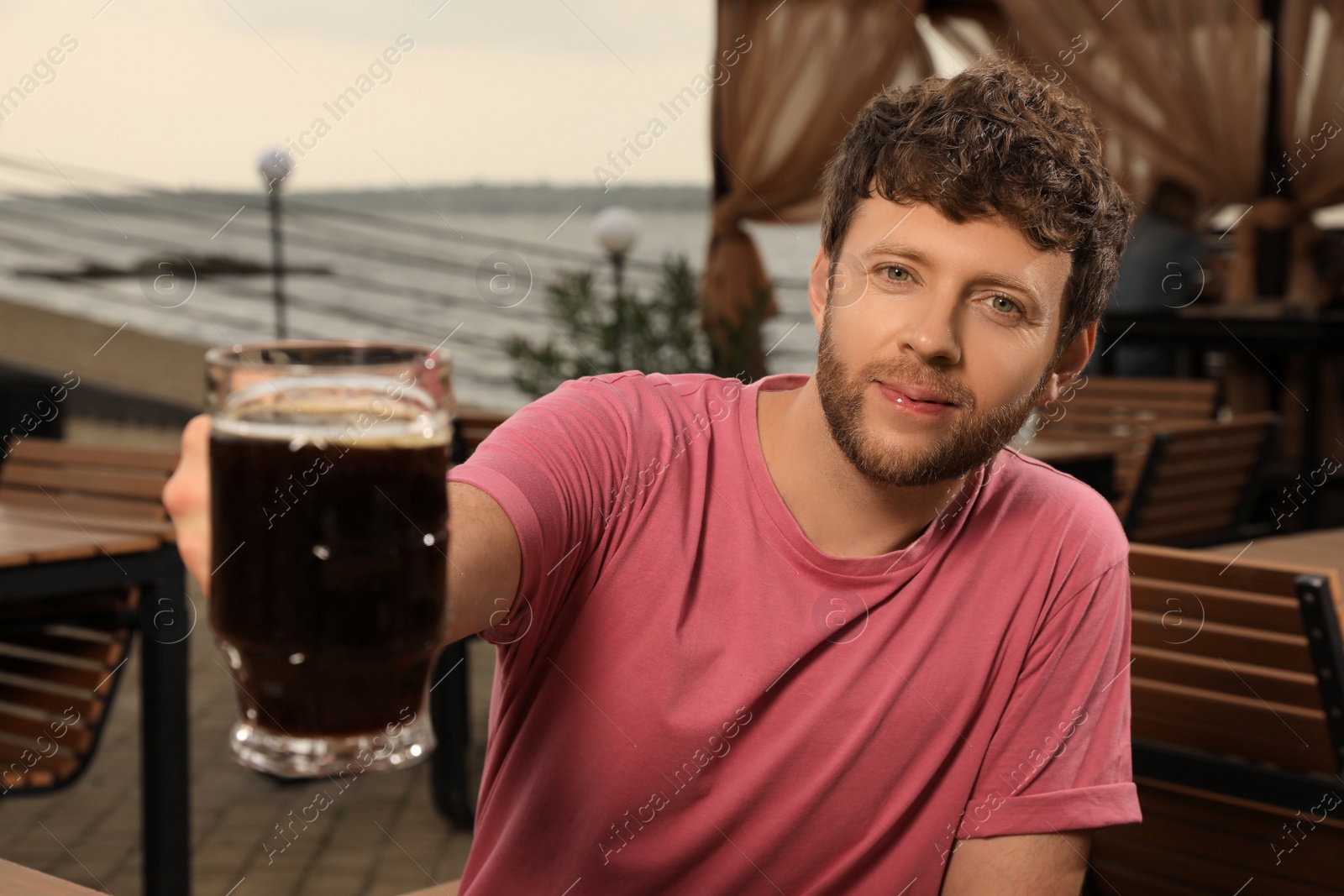 Photo of Man with glass of dark beer in outdoor cafe