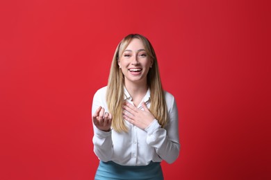 Photo of Beautiful young woman laughing on red background. Funny joke