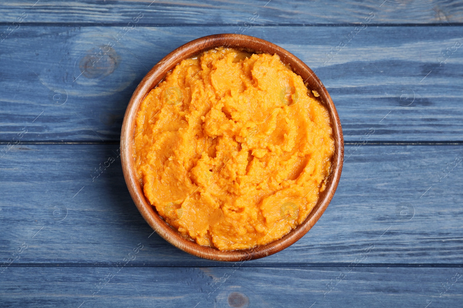 Photo of Bowl with mashed sweet potatoes on wooden background, top view