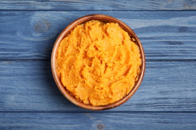 Bowl with mashed sweet potatoes on wooden background, top view