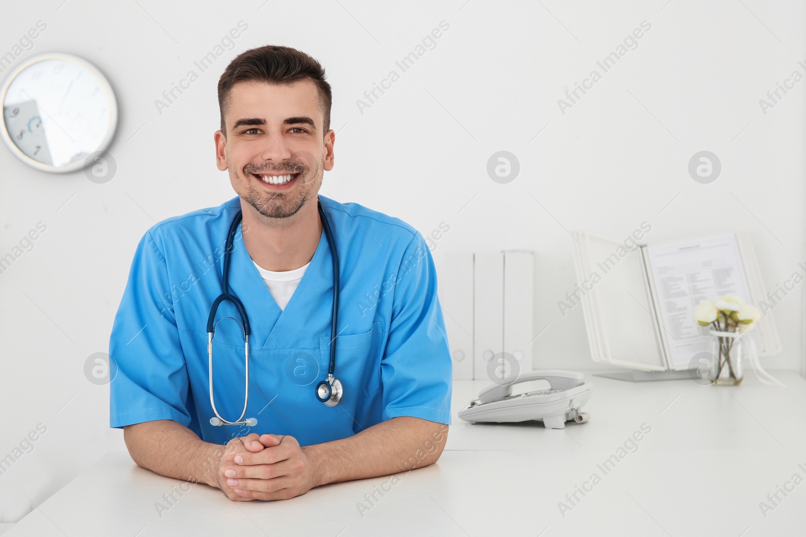 Photo of Young male doctor working at reception desk in hospital