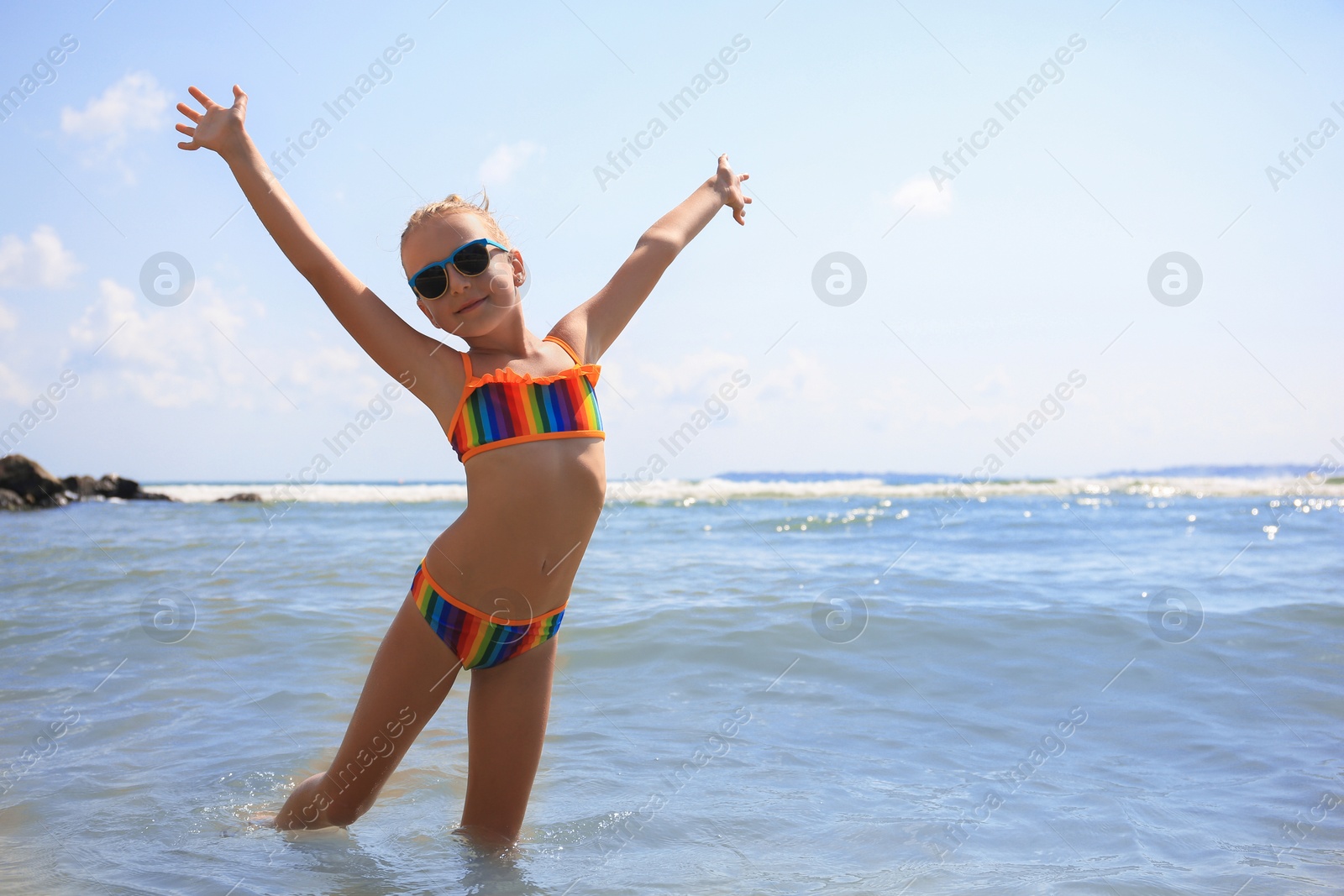 Photo of Little girl having fun in sea on sunny day, space for text. Beach holiday