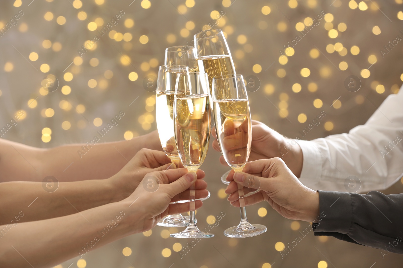 Photo of People clinking glasses of champagne on blurred background, closeup