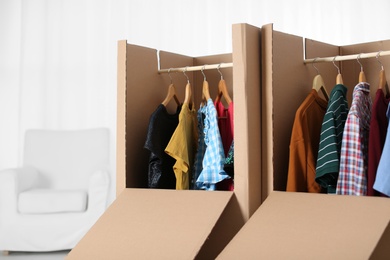 Photo of Wardrobe boxes with clothes on hangers indoors