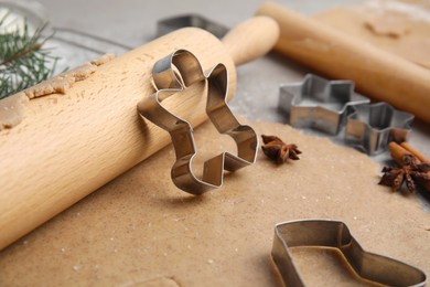 Photo of Homemade Christmas biscuits. Raw dough, rolling pin and cookie cutters on table, closeup