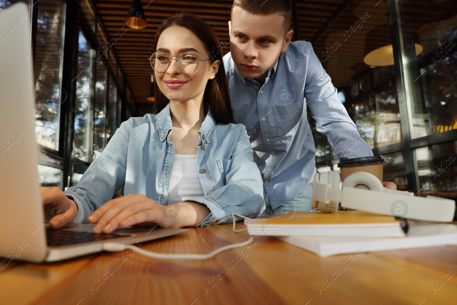 Photo of Young students with laptop studying at table in cafe