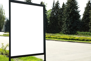 Photo of Blank advertising board on sidewalk in city. Mockup for design
