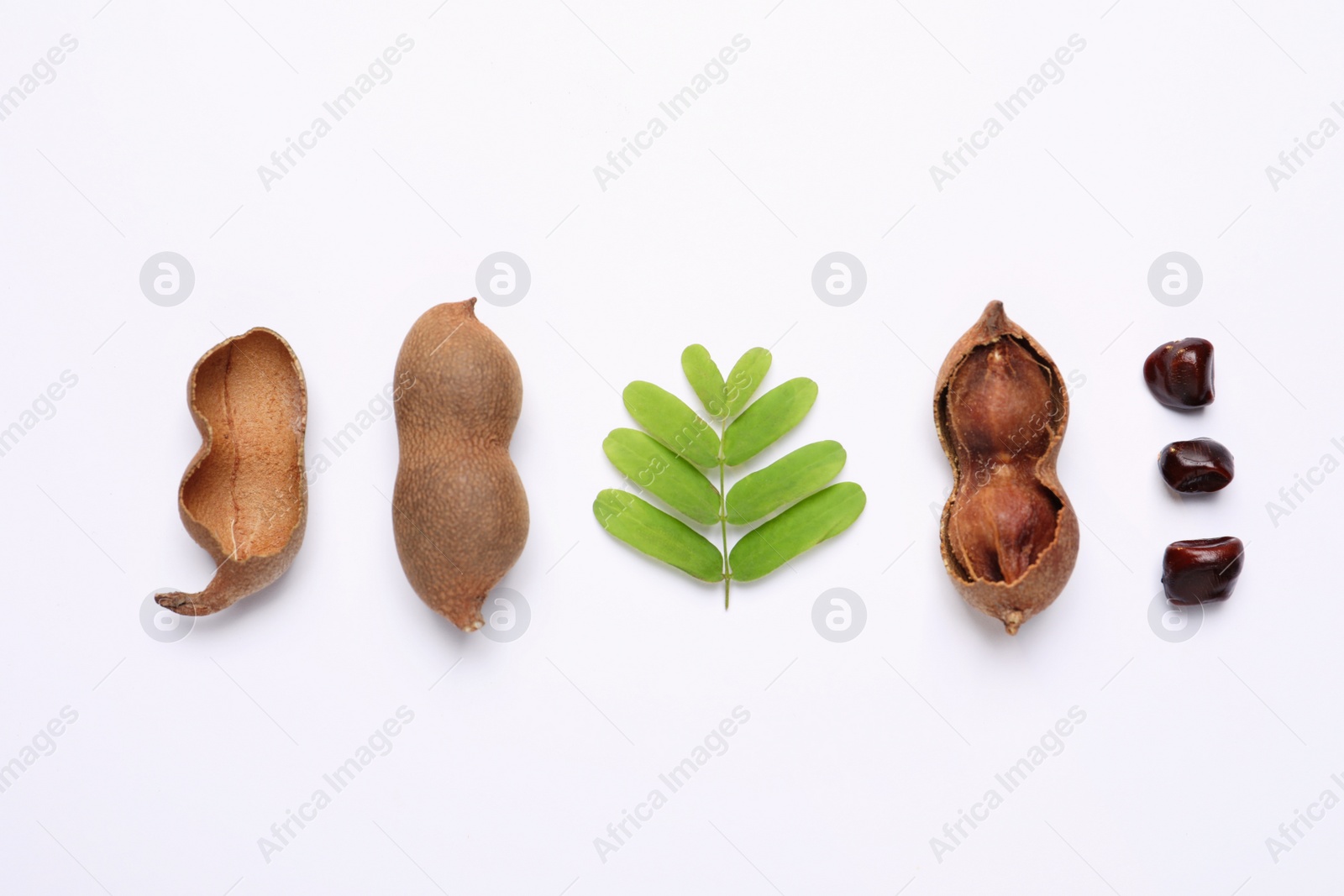 Photo of Delicious ripe tamarinds and leaves on white background, flat lay