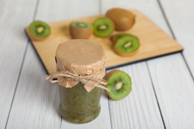 Photo of Jar of delicious kiwi jam and fresh fruits on white wooden table