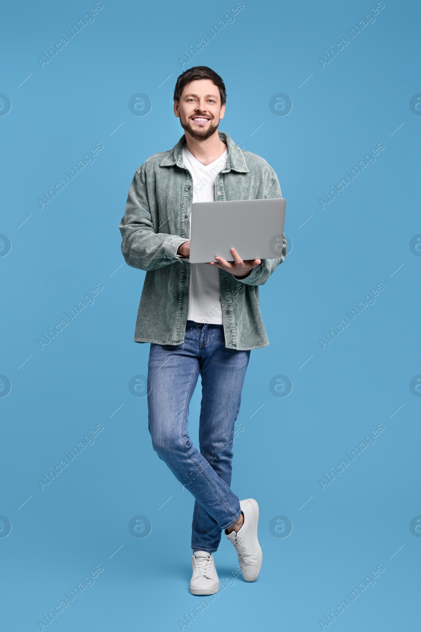 Photo of Happy man with laptop on light blue background