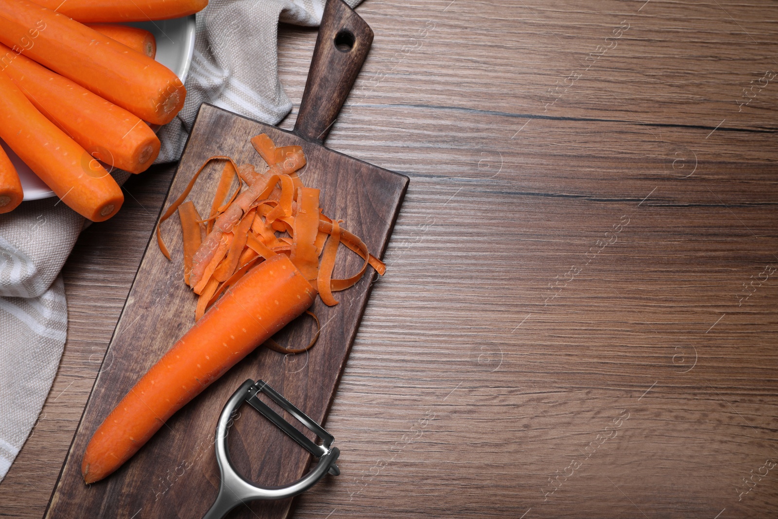 Photo of Peeled fresh carrot on wooden table, flat lay. Space for text