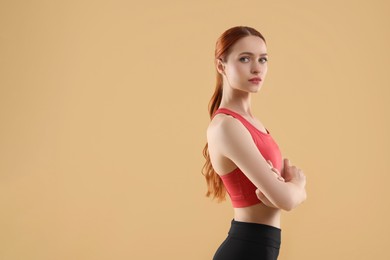 Young woman in sportswear on beige background, space for text