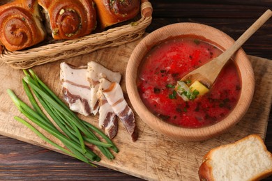 Photo of Delicious borsch served with pampushky and salo on wooden table, above view. Traditional Ukrainian cuisine
