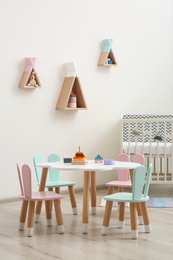 Photo of Little table and chairs with bunny ears in baby room. Interior design