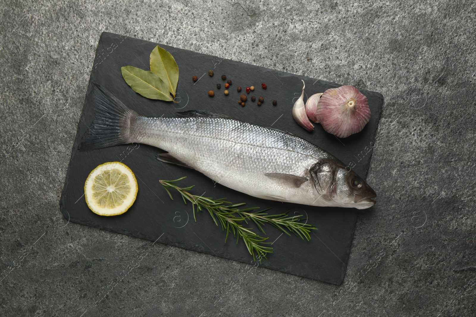 Photo of Sea bass fish and ingredients on grey table, top view