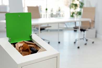 Photo of Open full trash bin in modern office, space for text. Waste recycling