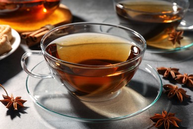 Photo of Aromatic tea with anise stars on light grey table, closeup