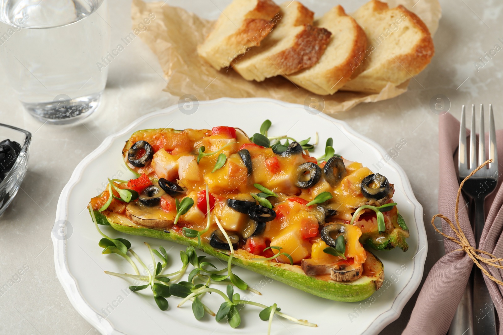 Photo of Baked stuffed zucchinis served on light grey table, closeup