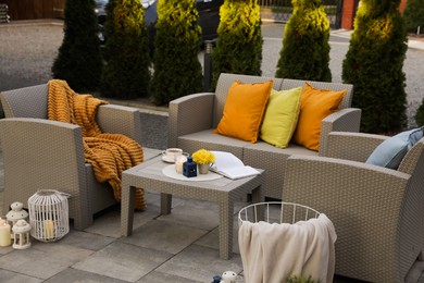 Beautiful rattan garden furniture, soft pillows and different decor elements in backyard