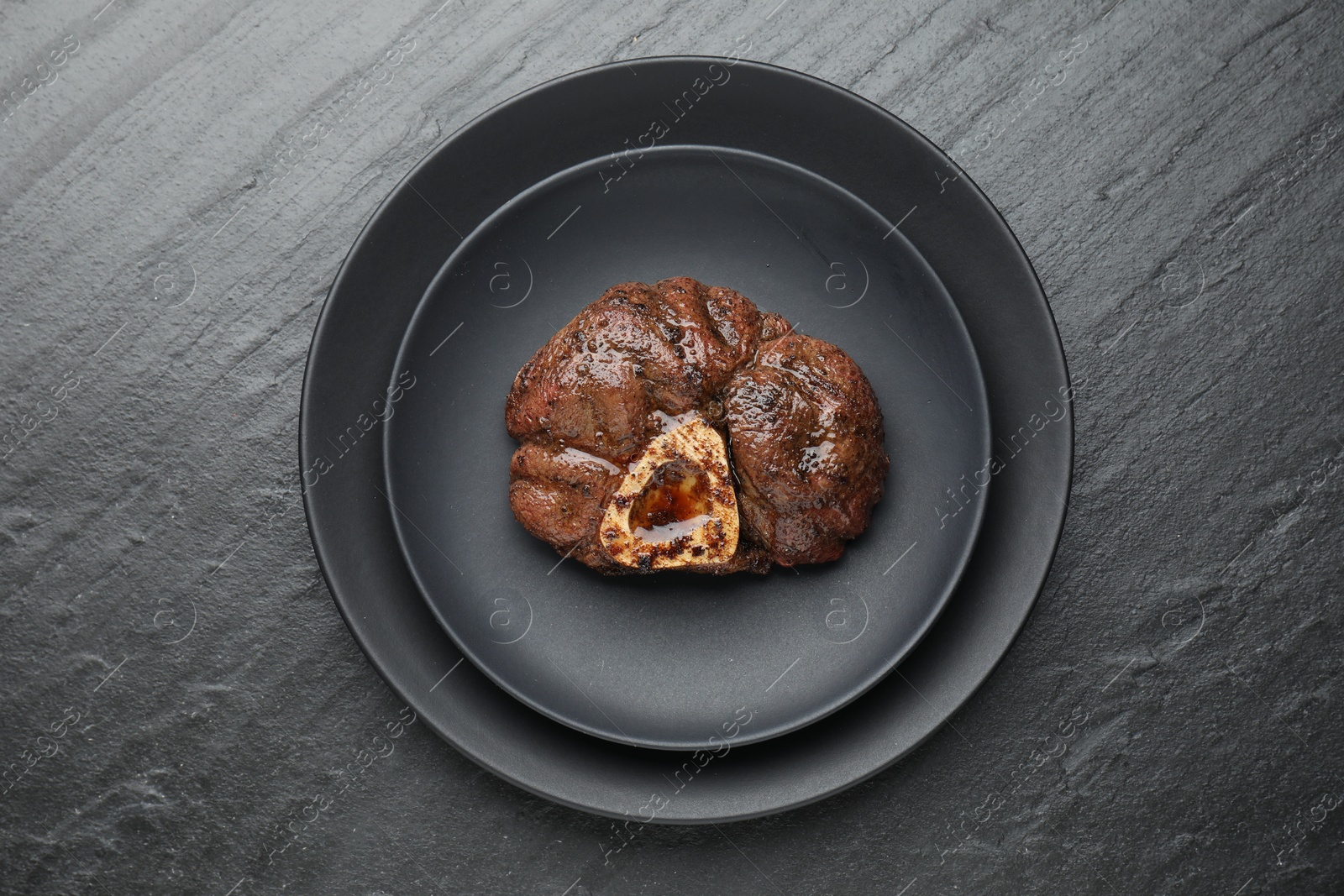 Photo of Piece of tasty grilled beef meat on black table, top view